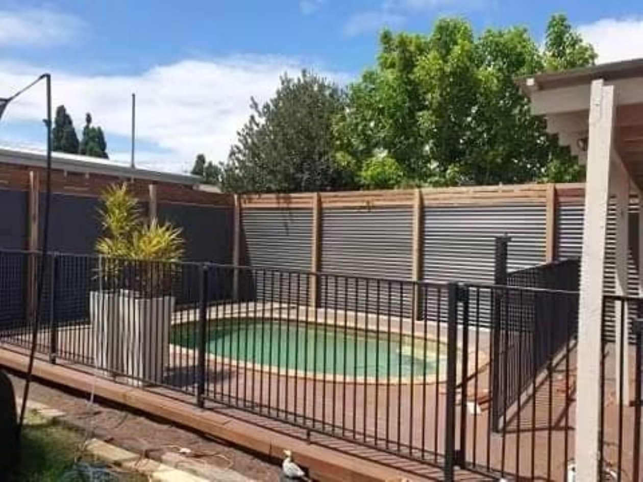 Colorbond and timber boundary fence around a pool area by Mordy Fencing